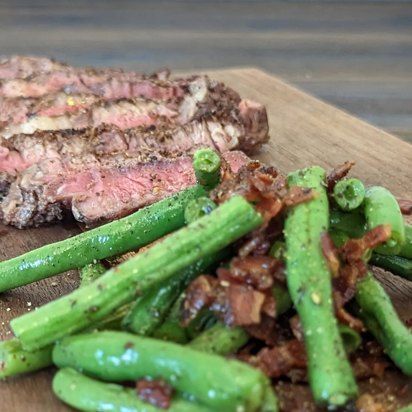 Ribeye with green beans and baconA quick lunch, yes lunch, as a test cook for a photo and video shoot I am excited for over the next week or two. This is a great meal that came together in about 15 minutes (once the grill was preheated). That was a win in itself, but the goal was to understand lighting and I was able to confirm a few layouts that worked and didn't work for me. I'll be excited to do the real cook, may change the protein, may add a sauce for some color, and definitely going to shift to an evening shoot for more controlled light. I want to get the moody feel and haven't don't that style in a while. It's over due. Test cook was a @butcher_box ribeye seasoned with @neilsarap Original beef and fresh cracked pepper using my @hexclad Pepper Grinder. Cooked over direct flame with @bearmountainbbq apple wood pellets. The green beans were cooked in the bacon grease, which is a home cured pepper bacon. Again some fresh pepper. Both the steak and green beans were finished with @spiceologyPink peppercorn and thyme rub. #steak #greenbeans #meatandveggies #keto #lowcarb #healthylunch #grilled #ribeye