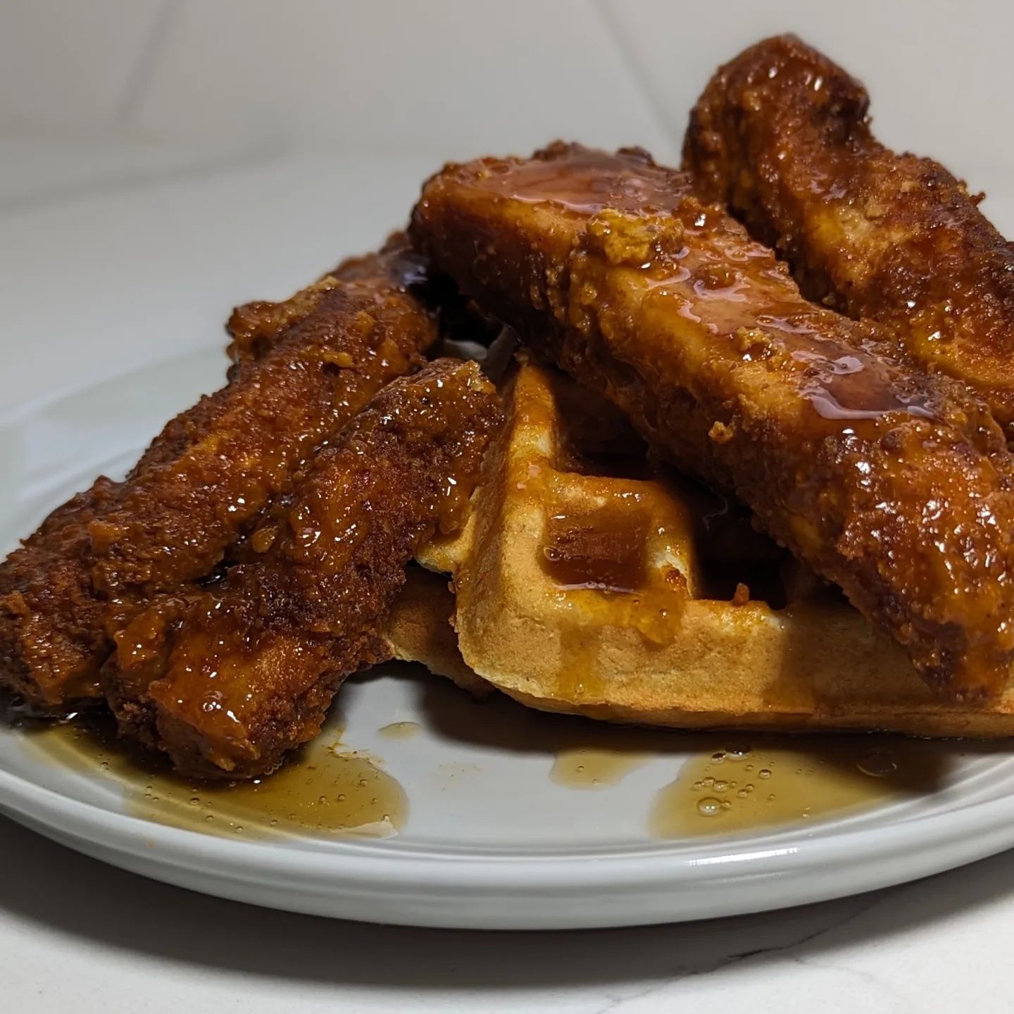 Chicken and wafflesCan you believe this chicken and waffle dish is low carb? Me neither, but it is! It starts with @realgoodfoods chicken strips. I baked them at 400 degrees about 30 min total, 15 min a side and then tossed them in @primalkitchenfoods buffalo sauce and put them back in the oven (off) just to stay warm while I cooked the waffles. The waffles are @birchbenders cooked in my @bydash no mess waffle maker. To plate I stacked the chicken high atop some buttered waffles and gave everything a drizzle of the Birch Benders keto syrup. These were perfectly balanced sweet and spicy, with an amazing fluffy waffle. This was a really easy meal, quick cleanup and absolutely delicious. #chickenandwaffles #lowcarbmeals #mealinspo #mealideas #easydinner #birchbenders #realgoodfoods #friedchicken #waffles #ketofood