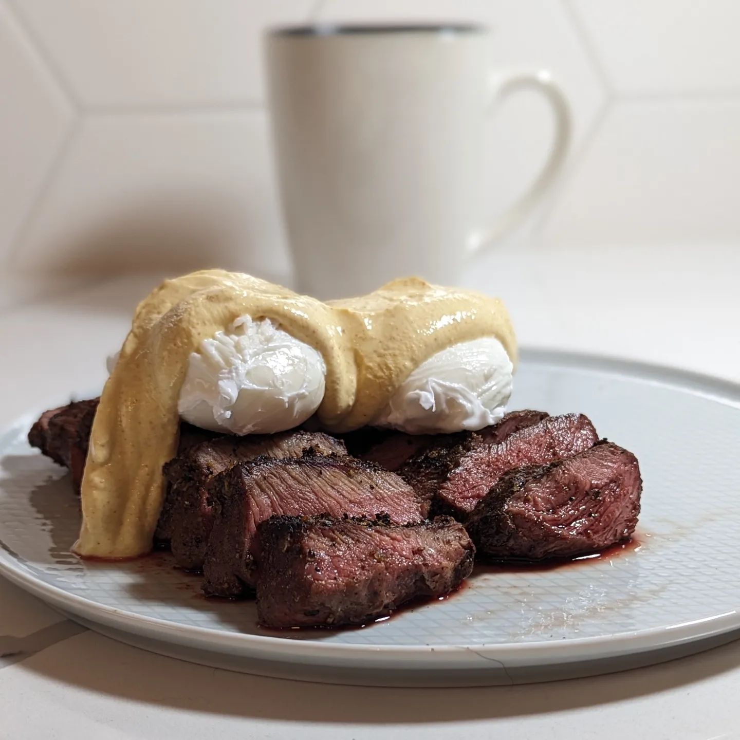 Happiness is steak and eggs for breakfast Flat iron steaks grilled in the @yodersmokers ys640s using @bearmountainbbq bourbon blend pellets. Seasoned with @neilsarap original beef. While the steaks were grilling I poached two eggs (light rolling boil, 3:30 seconds does it for me) with a touch of vinegar in the water. The sauce over the top was roughly (eyeballed it) 1/4 cup @fage 5% Greek yogurt, 1 teaspoon @pepperexchange aji Amarillo puree, 1/4 teaspoon smoked  paprika and 1/4 teaspoon tumeric. This is a high protein low carb meal to get the metabolism off to the right start. A little spicy in the sauce with some turmeric really kicks things off the right way. Served with a coffee and everything is kicking off right! Swipe to see that perfect bite.