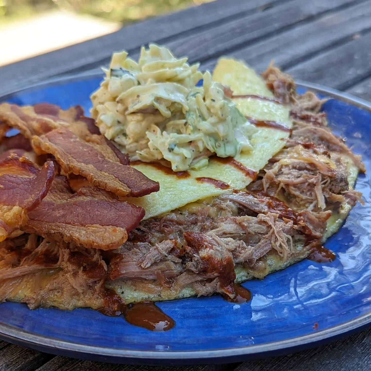 BBQ breakfast OmeletteWhen I think of a Classic BBQ item, it's a pulled pork sandwich. What happens when you want a pulled pork sandwich for breakfast? You turn it into an omelette! This three egg omelette is loaded with pulled pork, topped with coleslaw (a pulled pork pairing perfection) and served with a side of bacon! I avoid the traditional BBQ sauce as most contain a ton of sugar, and who needs sweet when you can go spicy! Hot sauce did the trick instead. #pulledpork #pulledporksandwich #breakfastideas #baconlovers