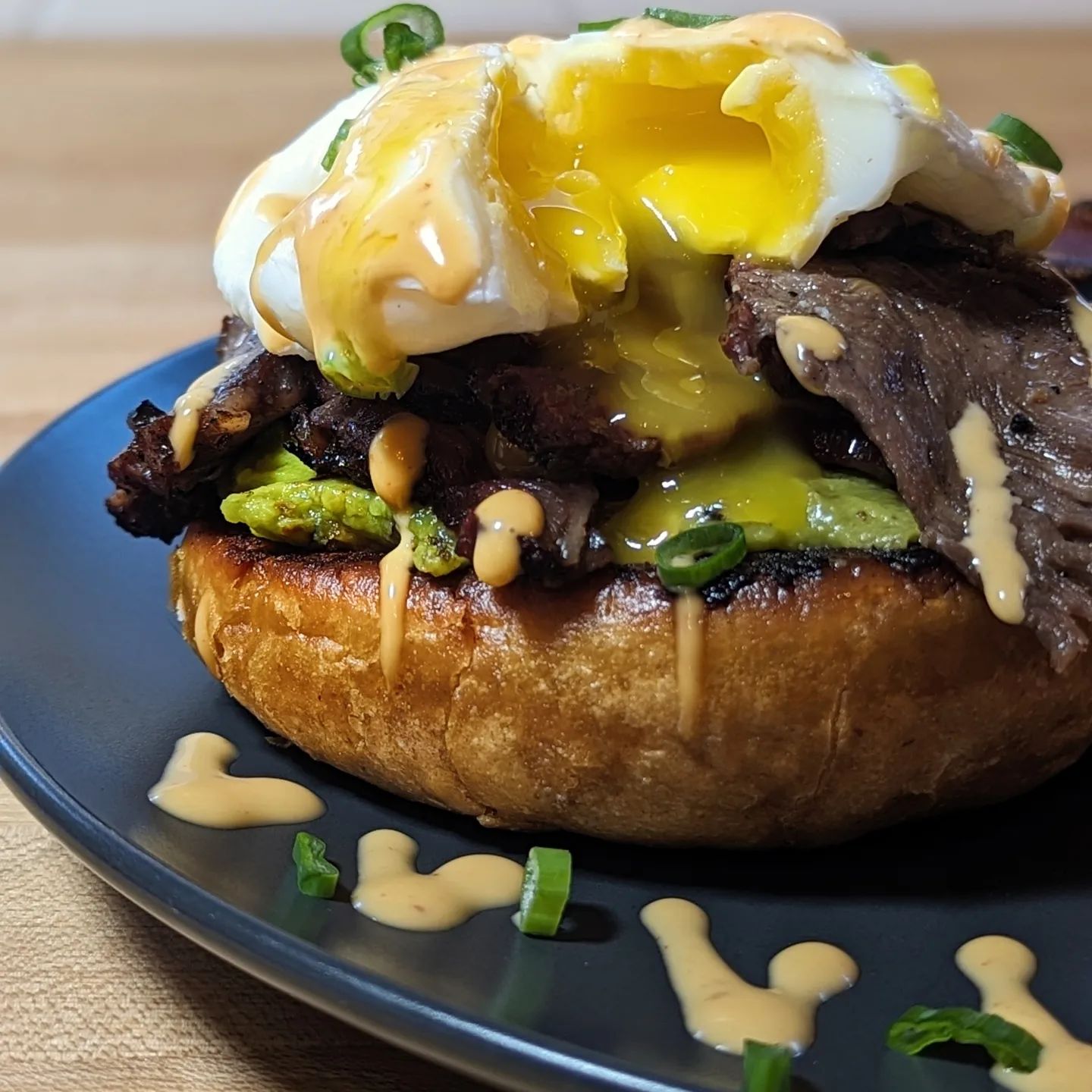 Low carb open face breakfast sandwich One @hero hamburger bun, toasted. A thick layer of @eatwholly avocado seasoned with @spiceology guac and roll. Smoked Ribeye steak with @bearmountainbbq bold blend, sliced thin and sauteed in some unsalted butter. Topped with a poached egg and garnished with @terrapinridgefarms bang bang sauce and green onions. Served with a side of bacon, because life is better with bacon. #poachedeggs #breakfasttime #brunchtime #avocadotoast #steakandeggs #bearmountainbbq #lowcarb #eatclean #eatrealfood #breakfastsandwich