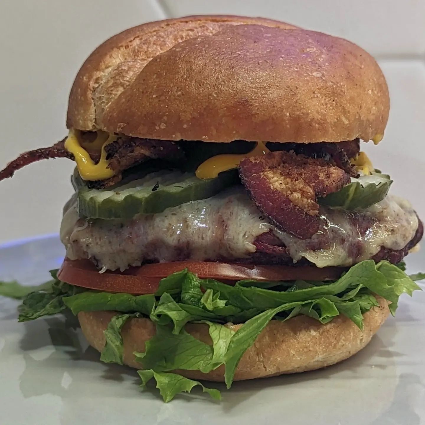 Classic Bacon CheeseburgerThe burger was grilled over direct @bearmountainbbq oak flame, with the bacon dripping from above. I seasoned the burger with @tdsbrewbbq Carne Sutra rub. When the burger was almost done I topped it with @cabotcreamery cheddar cheese. To assemble I loaded the @hero burger bun with shredded romaine lettuce, sliced tomatoes, the cheeseburger, @grillospickles and my home cured pepper bacon. The only condiment I needed was @frenchs mustard and I was all set.If you want to learn to make your own bacon, send me a DM and I'll reply with the instructions! #cheeseburger #baconcheeseburger #grilling #bearmountainbbq #baconmaking