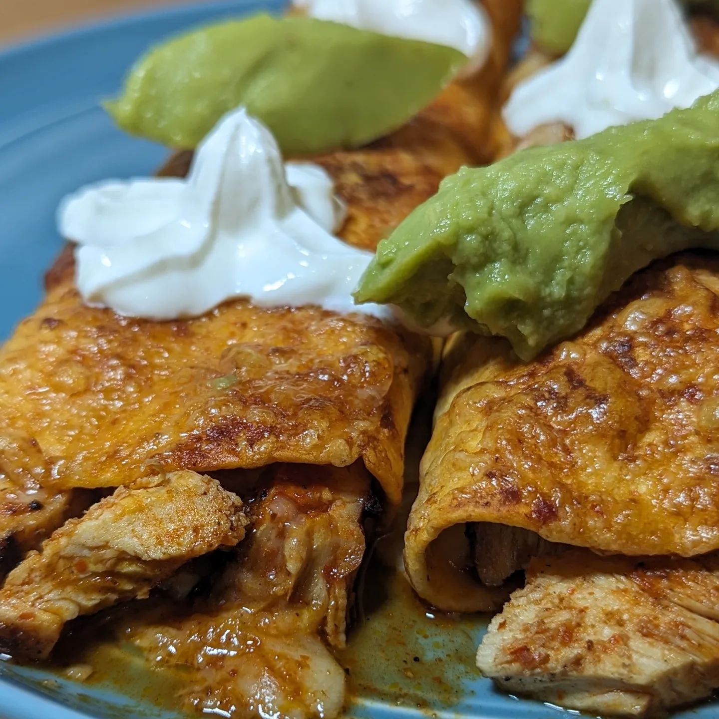 Grilled chicken enchiladasI posted these to my story yesterday and had a few folks ask how I made these. I started with boneless skinless chicken breasts and seasoned both sides with a mix of @tdsbrewbbq carne sutra and zesty taco rubs. While the seasoning was soaking in, I preheated the @yodersmokers to 375. Once the grill leveled out the temp I put the chicken on the grill grates over the @bearmountainbbq oak fueled fire (flames hitting the chicken for a little char). Flip the chicken to cook both sides and pull it off the grill when it hits 165. Let the chicken rest for a few minutes and then Dice up the chicken into small(ish) pieces.In a pan over medium high heat precook your tortillas and then coat the tortillas in enchilada sauce, I go with a full dunk. Roll the diced chicken(add a little of that enchilada  sauce to the chicken as well) and your favorite cheese (mine is @cabotcreamery these days) into the tortilla. If you're feeling fancy, you can add some grilled onions and or olives as well. From there place the rolled tortilla on a lined cookie sheet sprayed with some avocado oil. Top with a drizzle of sauce, some shredded cheese, sauce, and more cheese. Then place into an oven or toaster oven on broil at 400(medium if your broiler has low/medium/high) till cheese is crispy. Top with some sour cream, guac (I use @eatwholly packs to reduce waste) and enjoy!#enchiladas #enchiladarecipe #chickenenchiladas #lowcarb #easydinner #bearmountainbbq #grilledchicken